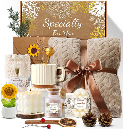 11-piece curated set including bath salts, scented candle, handmade soaps, soft blanket, fuzzy socks, tea set (mug + spoon + coaster), dried flower bouquet, sunflower potted decor, and blank greeting card